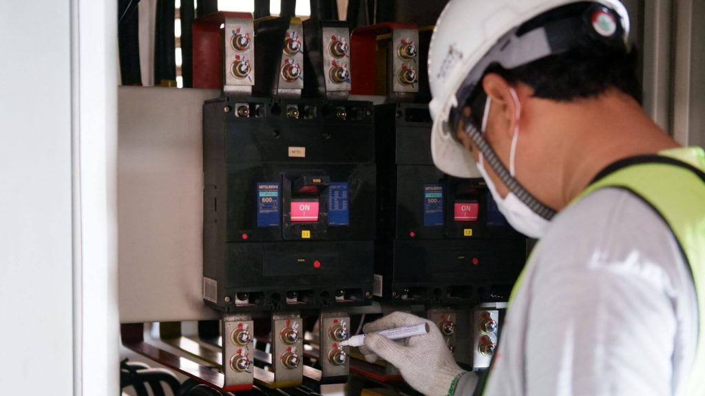 technicien qui intervient devant un tableau électrique