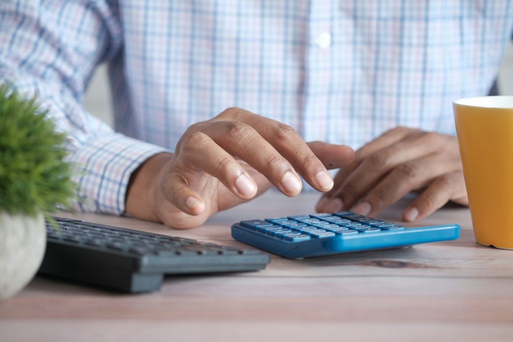 Personne utilisant une calculatrice pour estimer la surface constructible d’un terrain